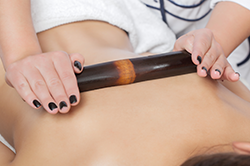 Masseuse using a bamboo roller to give a massage.